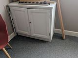 a room with a chair, a cabinet, and a window