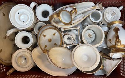 a basket full of white and gold dishes and cups