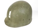 an old green helmet with holes on it sitting on a white surface