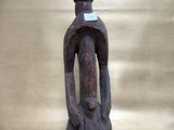 an old wooden statue of a man with a blue tag on it ' s neck