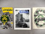 three old car brochures are displayed on a gray surface