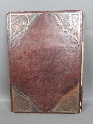 an old book with a leather cover on a gray surface