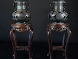 une paire de vases chinois anciens posés sur des socles, sur fond noir