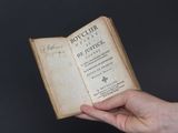 une personne tenant un livre à la main, entouré d'une chaîne