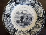 a black and white plate with a picture of a man riding a horse