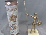 une statue représentant un homme tenant une lance à côté d'un vase