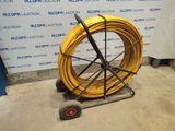 a yellow hose on a cart in front of a wall