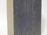an old book sitting on top of a white table next to a white wall