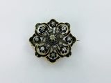 un gros plan sur une broche en forme de fleur dorée et noire