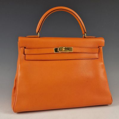 un sac à main en cuir orange avec des finitions dorées sur la poignée