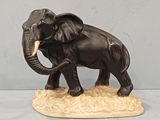 statue of an elephant with tusks and tusks standing on a rock