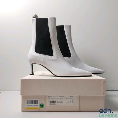 des bottines en cuir blanc posées sur une boîte avec un fond blanc