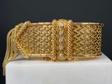 un gros plan d'un bracelet en or et diamants posé sur un bloc de marbre