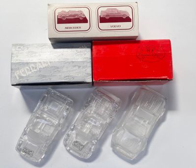 quatre petites voitures en plastique dans une boîte posée sur une surface blanche