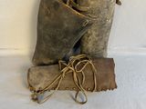 an old pair of boots and a leather bag on a white surface