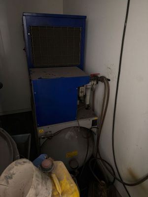 a small room with a blue machine and a yellow trash can