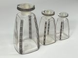 three glass bottles with silver lids on a white surface