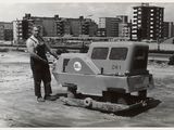 black and white photo of a man standing next to a construction vehicle
