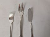 three forks and a knife on a white table