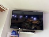 une télévision à écran plat fixée au mur au-dessus d'une étagère