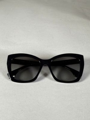 un gros plan sur une paire de lunettes de soleil noires posées sur une surface blanche