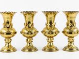 four gold vases sitting on top of each other on a white surface