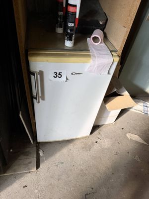 a small refrigerator that has a roll of toilet paper on top of it