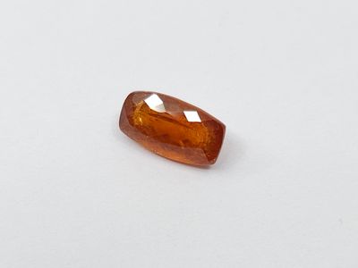 a close up of an orange sapphire stone on a white surface