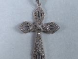 un pendentif en forme de croix en argent avec une chaîne, sur fond blanc