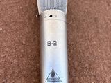 microphone argenté posé sur une moquette marron, avec une étiquette en noir et blanc