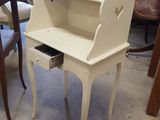 a small desk with a drawer on it in the middle of a room