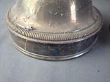 a silver bell sitting on top of a table next to a clock