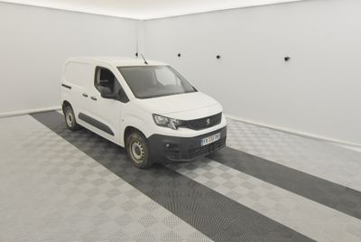 une camionnette blanche garée dans une pièce au sol en damier