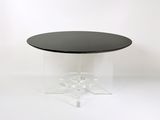 une image représentant une table avec un plateau noir et un piètement transparent