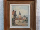framed picture of a painting of a village with a church in the background