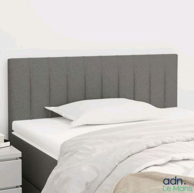 un lit avec une tête de lit grise et des draps blancs