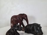 trois figurines d'éléphants et un hippopotame sur un fond blanc