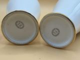 pair of white porcelain vases with gold rims sitting on a table