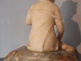 marble statue of a child sitting on a rock on a table