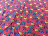 a close up of a red fabric with blue and yellow fruit on it