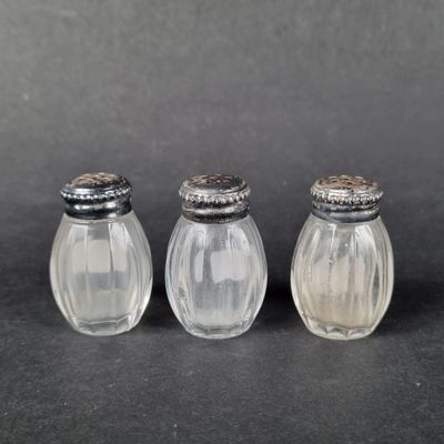 three glass salt and pepper shakers sitting on a black surface