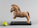 statue d'un cheval posée sur un socle, à côté d'une pomme verte
