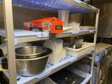 a metal shelf with bowls and pans on it in a kitchen