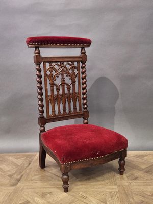 une chaise rouge posée sur un parquet, près d'un mur gris