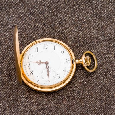 une montre de poche en or posée sur une surface marron