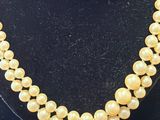 un collier de perles jaunes posé sur un présentoir noir pour mannequin