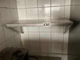 a dirty stove in a dirty kitchen with a shelf above it