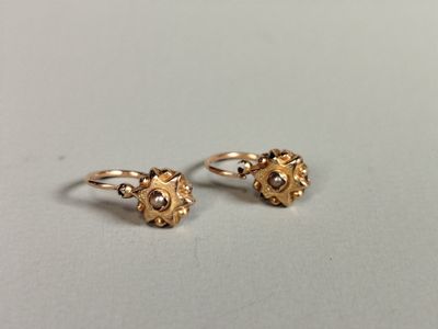 a pair of gold earrings with pearls on them sitting on a table