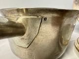 a silver pot and a silver cup on a white table