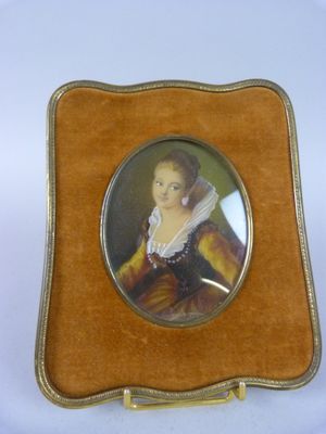 une vieille photo représentant une femme en robe marron, assise dans une caisse en bois